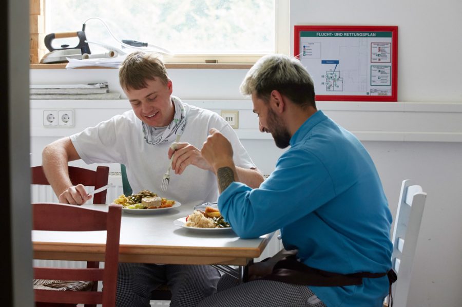 In einem Nebenraum der Küche nehmen Nico und Guiliano gut gelaunt ihr Mittagessen zu sich.