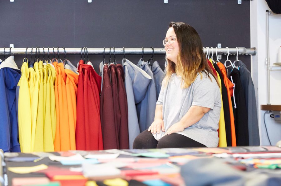 Nadine sitzt im Interview vor einem Ständer mit Hoodies der aktuellen wasni-Kollektion.